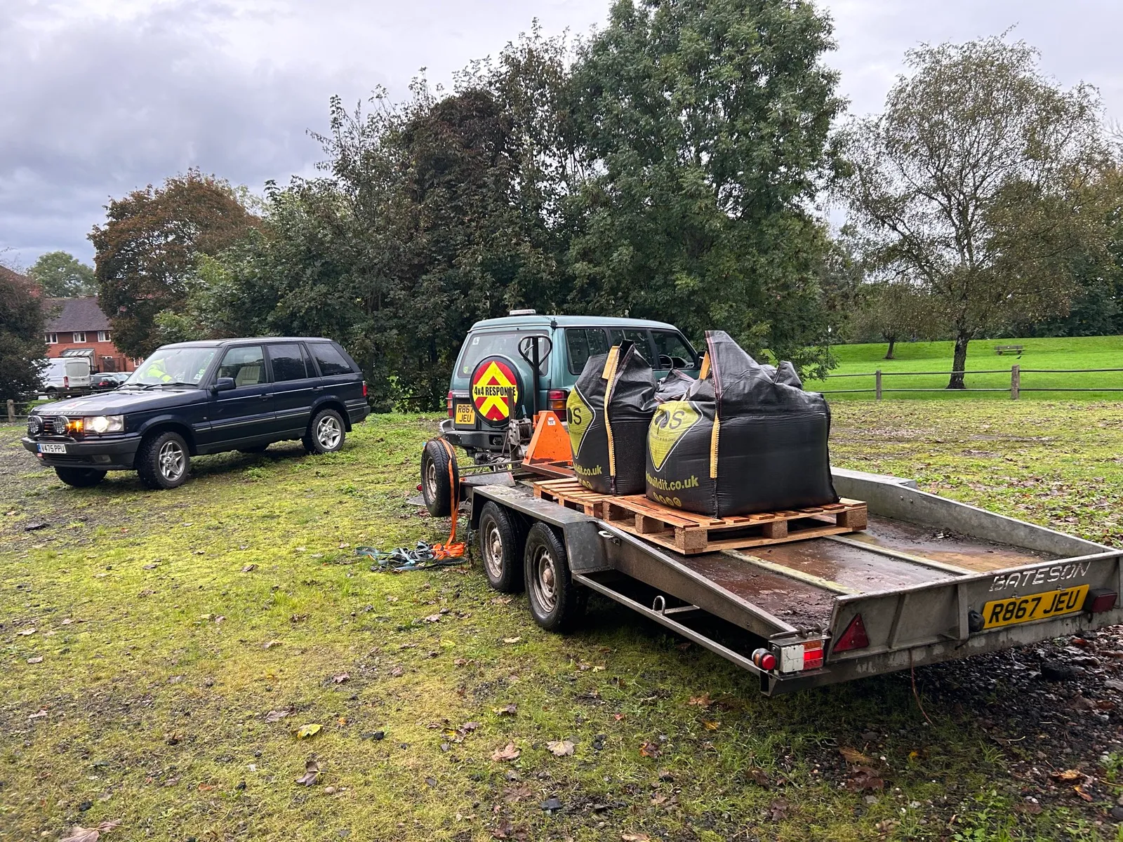 A Range Rover and the loaded trailer lined up on wet grass